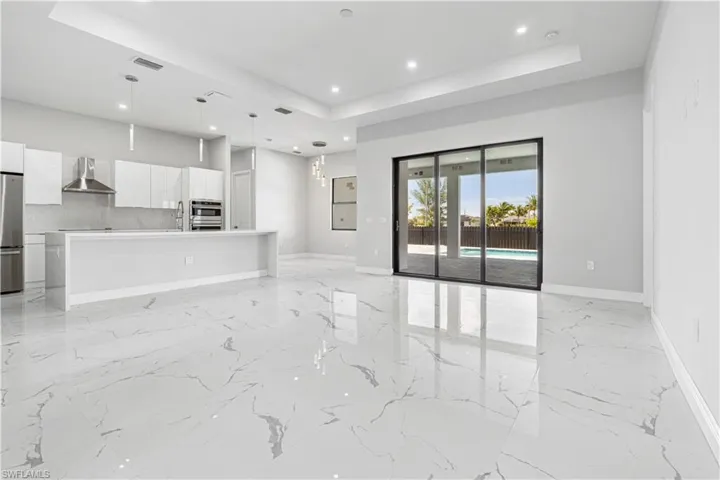 Open floorplan living room area with access to the fully-fenced yard and pool area.
