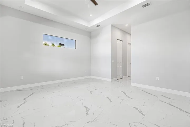 Master bedroom featuring a tray ceiling and light tile flooring