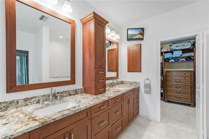 The primary ensuite bath showcases a granite countertop with dual vanities and shaker-style cabinetry, providing abundant storage. Custom walk in closet.