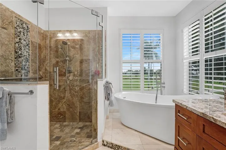 The primary ensuite bath features a freestanding soaking tub, a walk-in shower with a seamless glass enclosure, and elegant porcelain tile accented with a stunning listello.