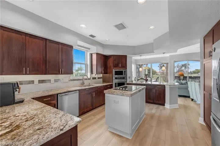 A chef’s dream kitchen featuring two-toned shaker-style wood cabinetry, stainless steel appliances, a center island, subway tile backsplash, under-cabinet lighting, and a tray ceiling.