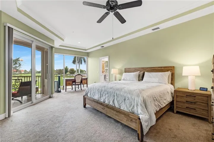 The primary bedroom features direct lanai access, a picture window, tray ceiling, plush carpet, and an ensuite bathroom.