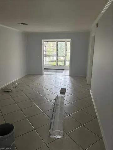 Tiled empty room featuring ornamental molding