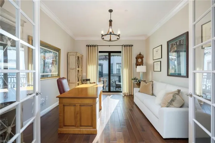 Office area featuring french doors, dark wood-type flooring, crown molding, and hanging lights