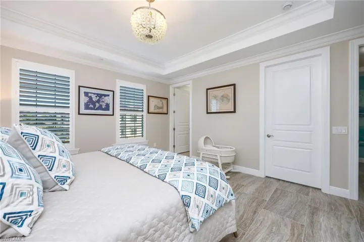 Bedroom with a raised ceiling, crown molding, and hanging lights