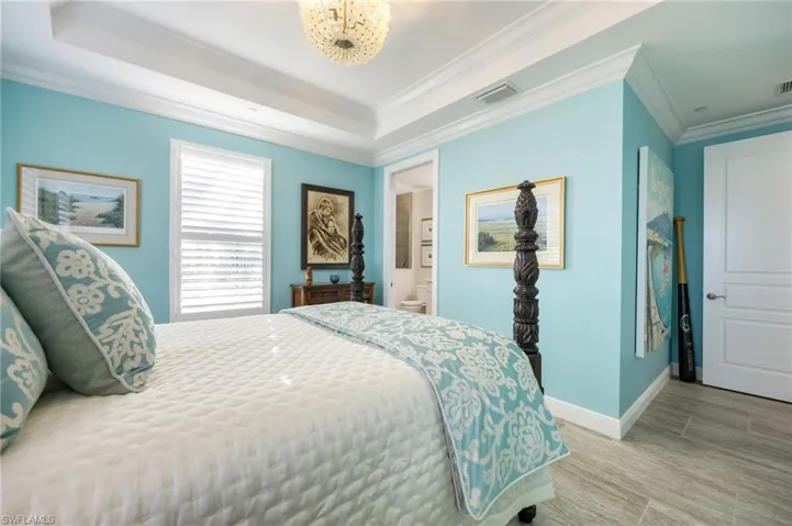 Bedroom with crown molding, wood finish floors, and ensuite bath