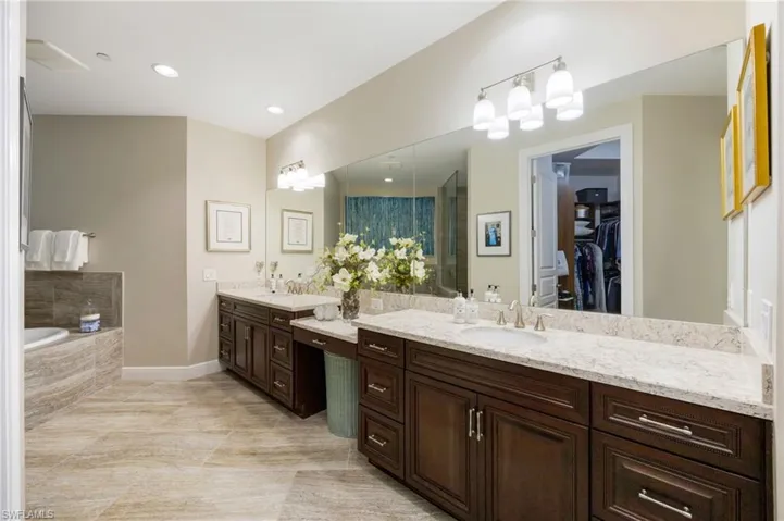 Full bathroom featuring two vanities, a walk in closet, a bath, and recessed lighting