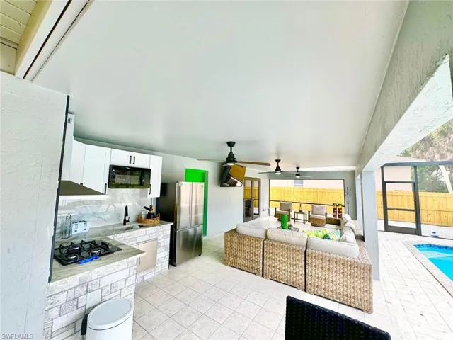 Kitchen with white cabinetry, black appliances, decorative backsplash, a ceiling fan, and light tile patterned floors
