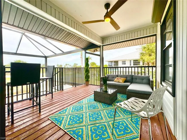 Wooden deck featuring an outdoor hangout area, ceiling fan, and a lanai