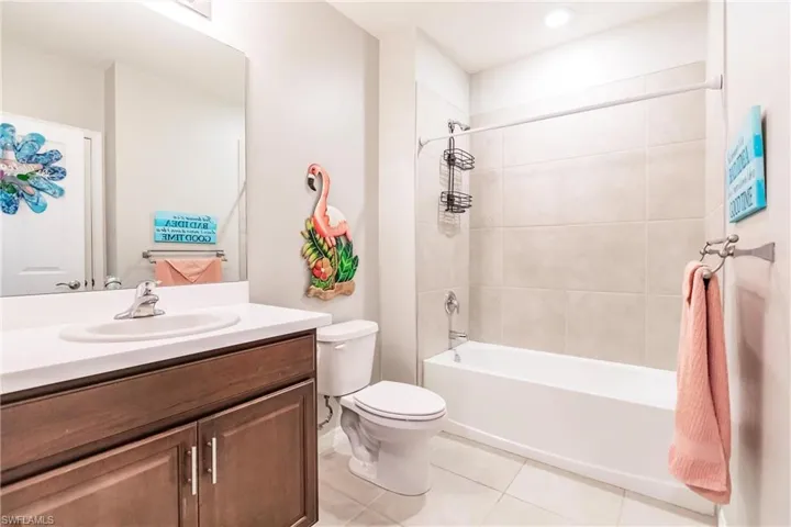 Full bathroom with tile patterned flooring, vanity, tiled shower / bath combo, and toilet
