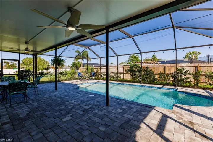 View of pool with a patio, glass enclosure, and ceiling fan