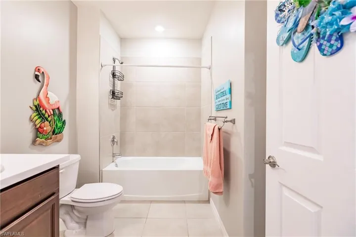 Full bathroom featuring tile patterned flooring, vanity, toilet, and tiled shower / bath