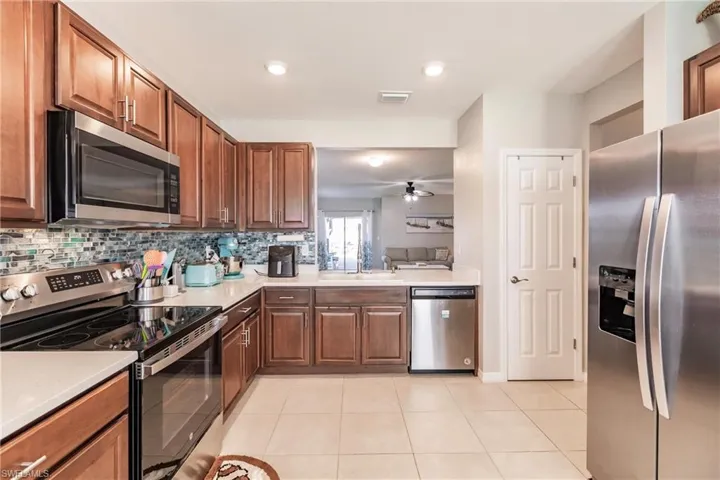 Kitchen with sink, ceiling fan, light tile patterned floors, tasteful backsplash, and stainless steel appliances