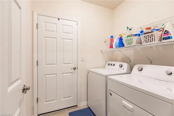 Laundry room with washing machine and dryer and light tile patterned floors