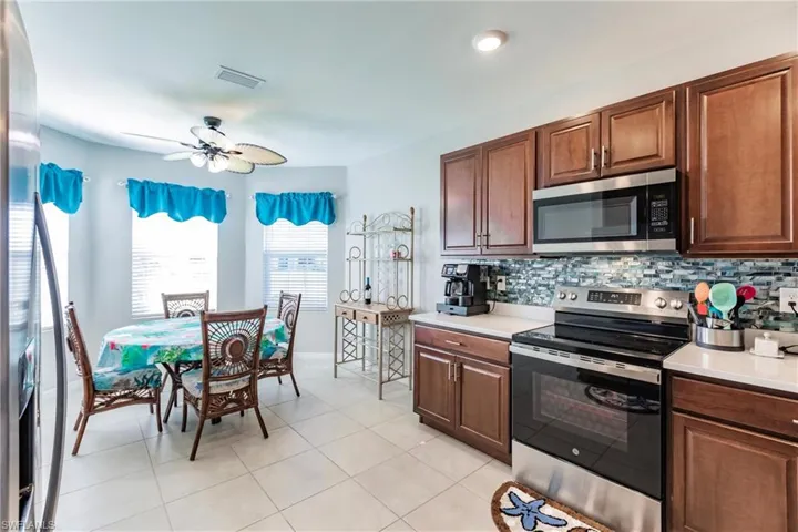 Kitchen featuring ceiling fan, light tile patterned floors, stainless steel appliances, and tasteful backsplash