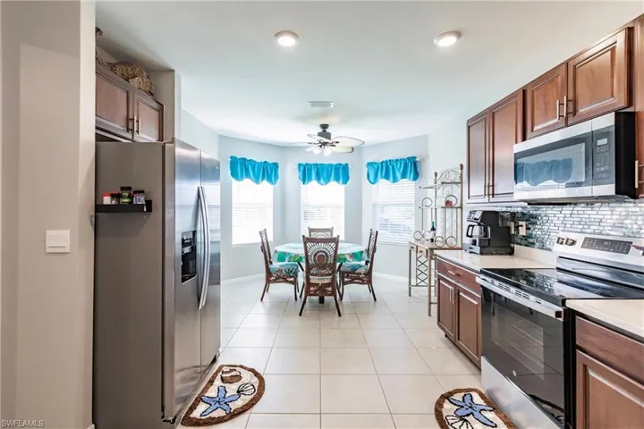 Kitchen with tasteful backsplash, ceiling fan, light tile patterned flooring, and appliances with stainless steel finishes