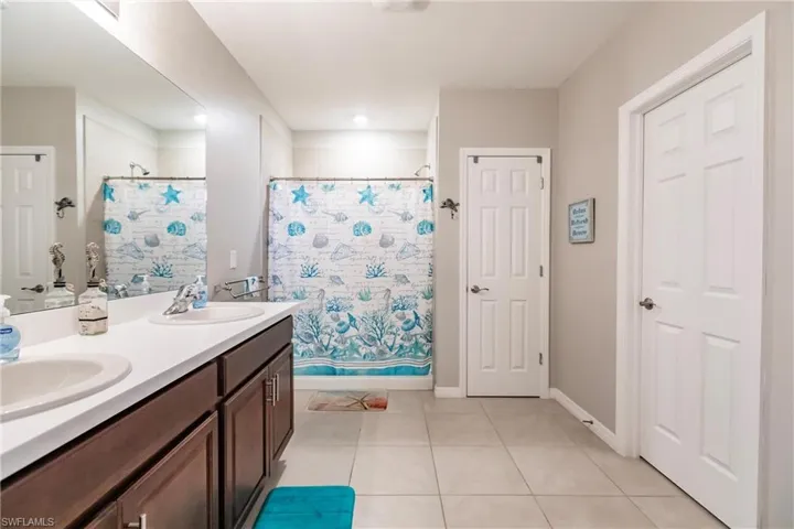 Bathroom featuring tile patterned flooring, shower / bath combination with curtain, and vanity