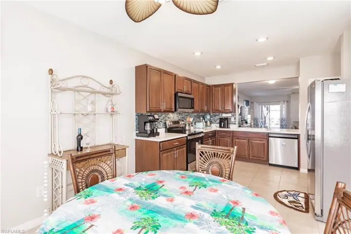 Kitchen with decorative backsplash, light tile patterned floors, stainless steel appliances, and ceiling fan