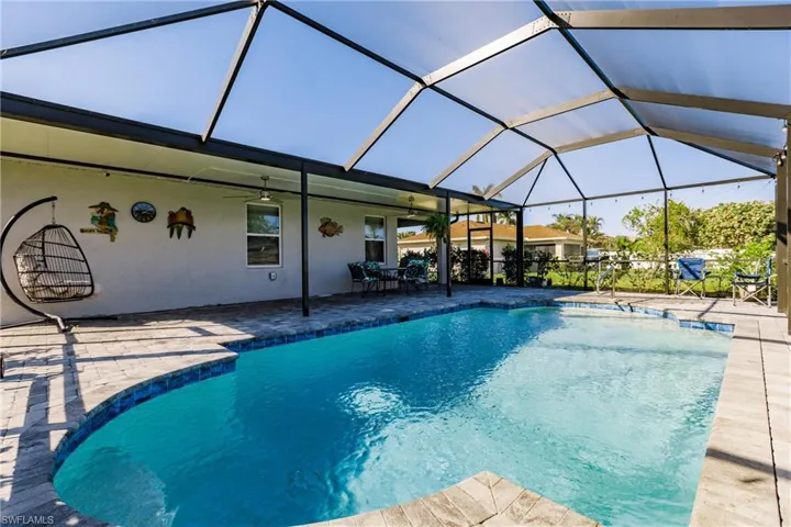 View of pool with glass enclosure, ceiling fan, and a patio