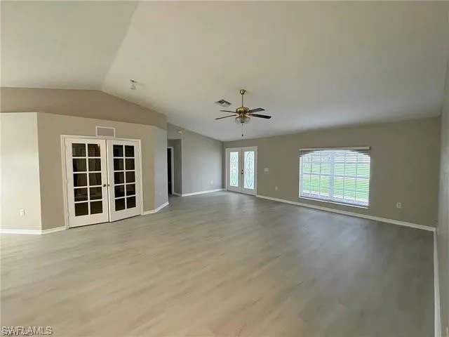 Spare room featuring french doors, light wood-style flooring, vaulted ceiling, and a ceiling fan