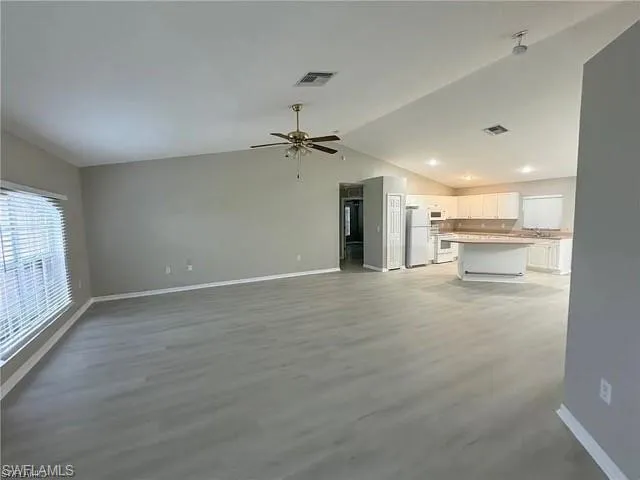 Unfurnished living room with lofted ceiling, a ceiling fan, and light wood finished floors