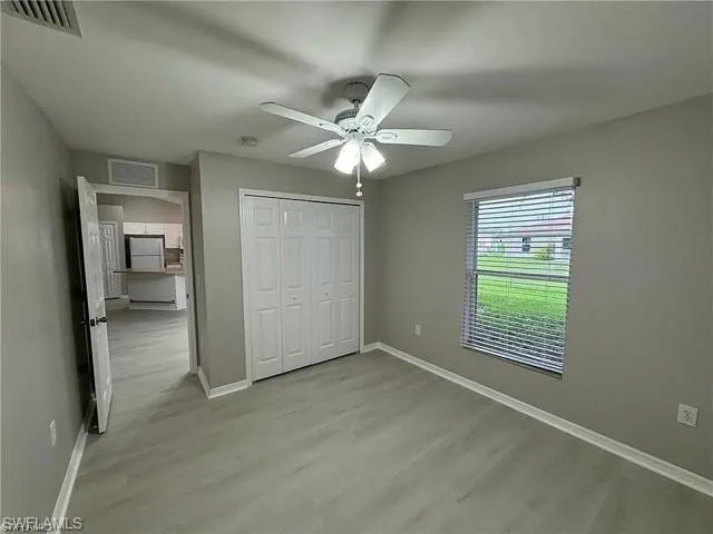 Unfurnished bedroom featuring light wood-style floors, a closet, and ceiling fan
