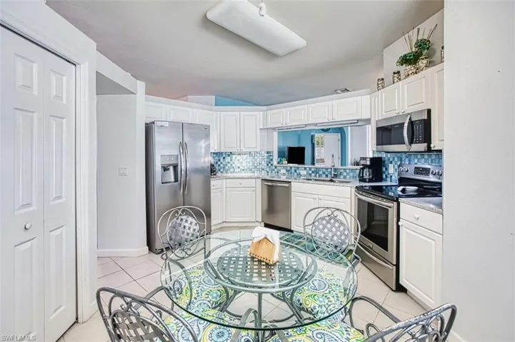 Kitchen featuring appliances with stainless steel finishes, white cabinetry, decorative backsplash, and light tile patterned floors
