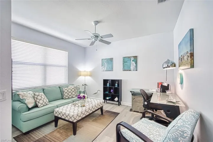 Living area with wood finished floors, a ceiling fan, and an office area