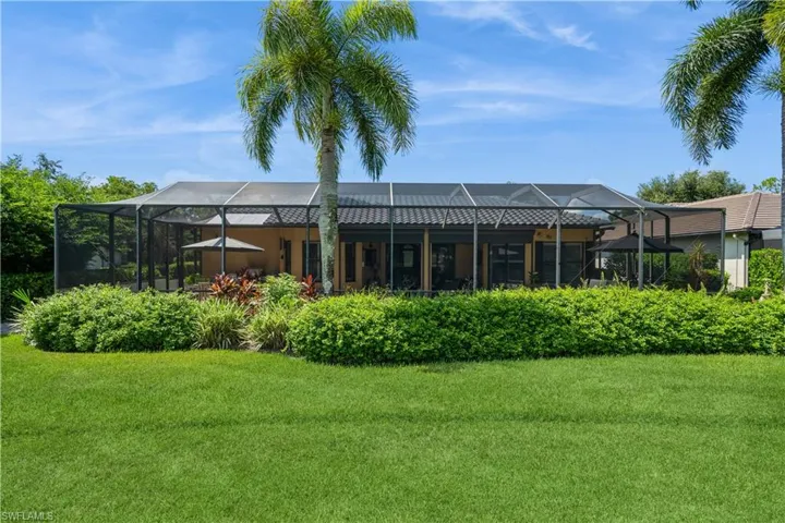 Rear view of property featuring a lanai and a lawn