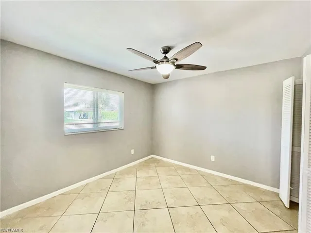 Room featuring large format tile flooring, a window with horizontal blinds, and a ceiling fan with integrated lighting