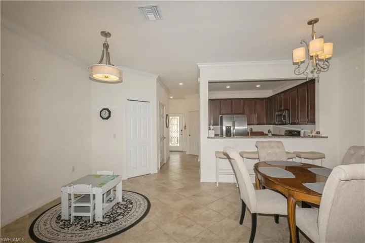 Tiled dining space with an inviting chandelier and ornamental molding