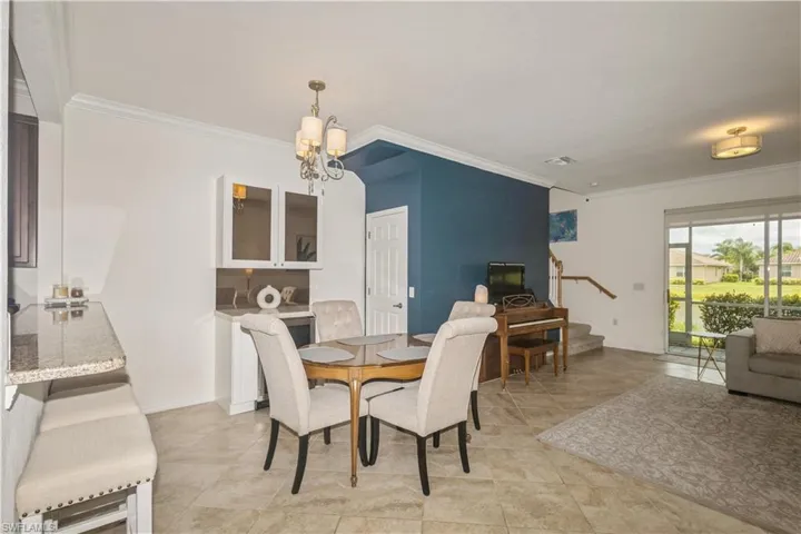 Tiled dining room featuring a notable chandelier and ornamental molding