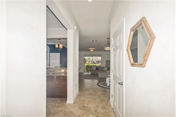 Hall featuring ornamental molding, light tile flooring, sink, and a chandelier