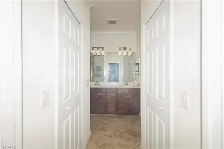 Bathroom featuring tile floors, ornamental molding, large vanity, and dual sinks