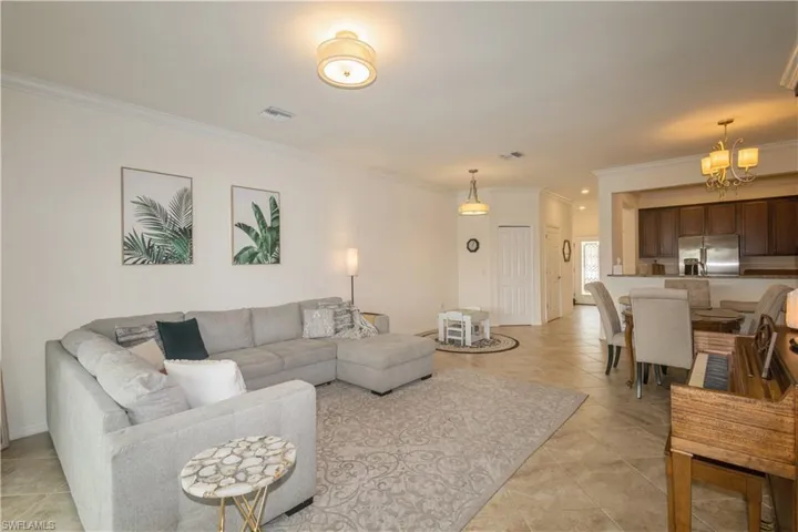 Living room featuring crown molding, a chandelier, and light tile floors