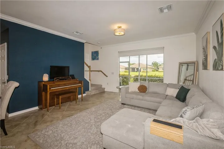 Living room featuring tile floors and crown molding
