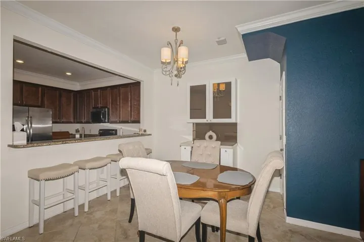 Dining room featuring a notable chandelier, sink, crown molding, and light tile flooring