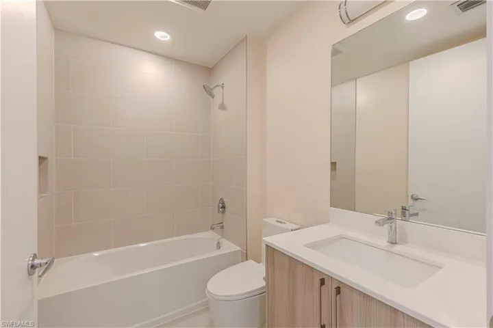 Full bathroom with vanity, tiled shower / bath combo, and toilet
