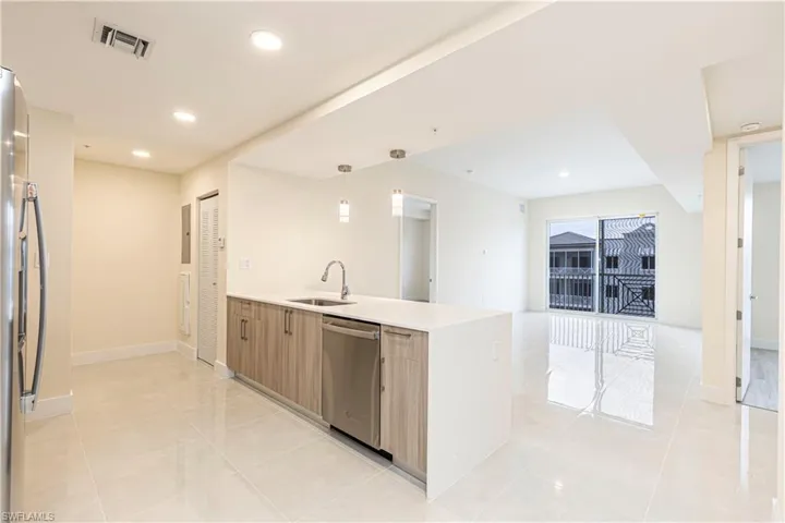 Kitchen with stainless steel appliances, sink, light tile patterned floors, kitchen peninsula, and pendant lighting