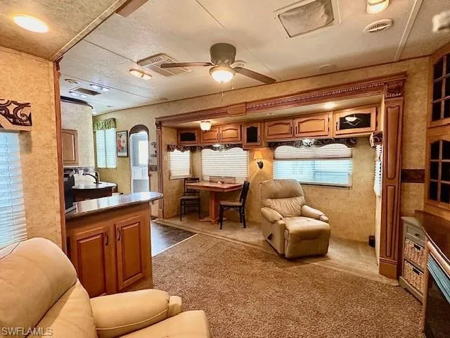 Carpeted living room with ceiling fan