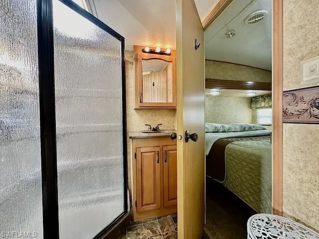 Bathroom with tile floors, a shower with shower door, and vanity
