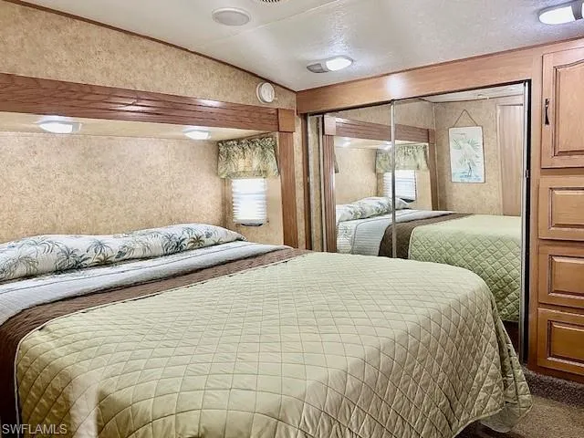 Bedroom with vaulted ceiling, a closet, a textured ceiling, and carpet floors