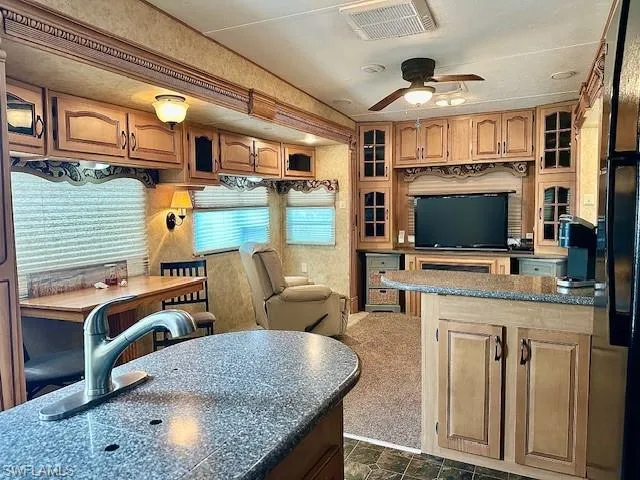 Kitchen featuring dark colored carpet and ceiling fan