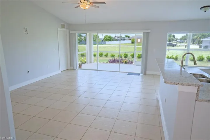 Living room with light tile patterned floors, vaulted ceiling, and ceiling fan