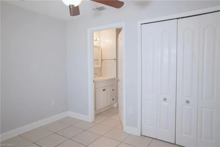 Bedroom #1 with bifold closet doors, ceiling fan, and window with view of the backyard.