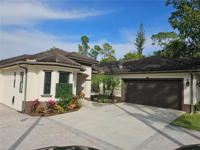View of front of home with stucco siding, driveway, a garage, and a tile roof