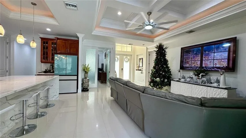 Living area with coffered ceiling, ornamental molding, a ceiling fan, beamed ceiling, and recessed lighting