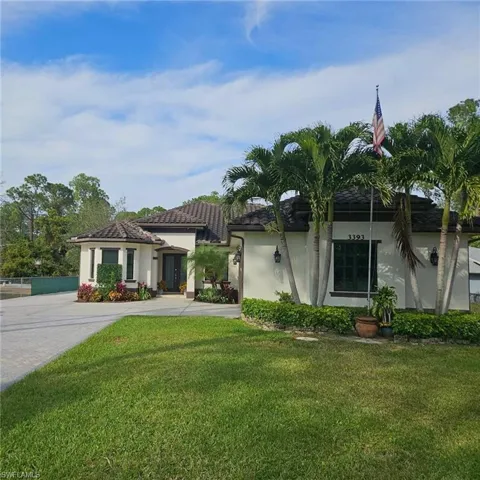 View of front of house with a front yard, stucco siding, and driveway
