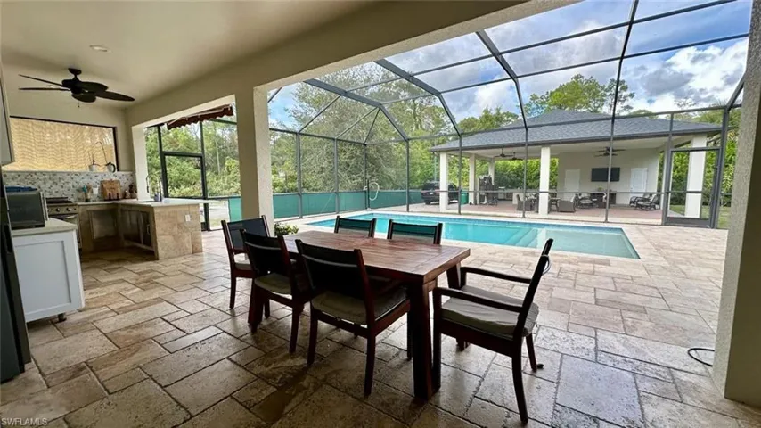 Outdoor pool with area for grilling, a patio area, a sunroom, a lanai, and outdoor dining space