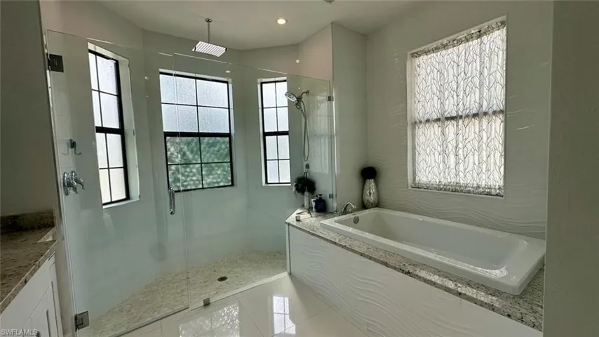 Bathroom featuring a garden tub, a stall shower, and light tile patterned floors
